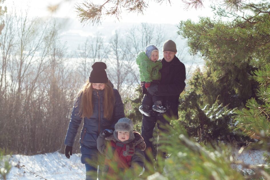 A family with two children is walking in the winter forest. Hiking in the snow through the forest.