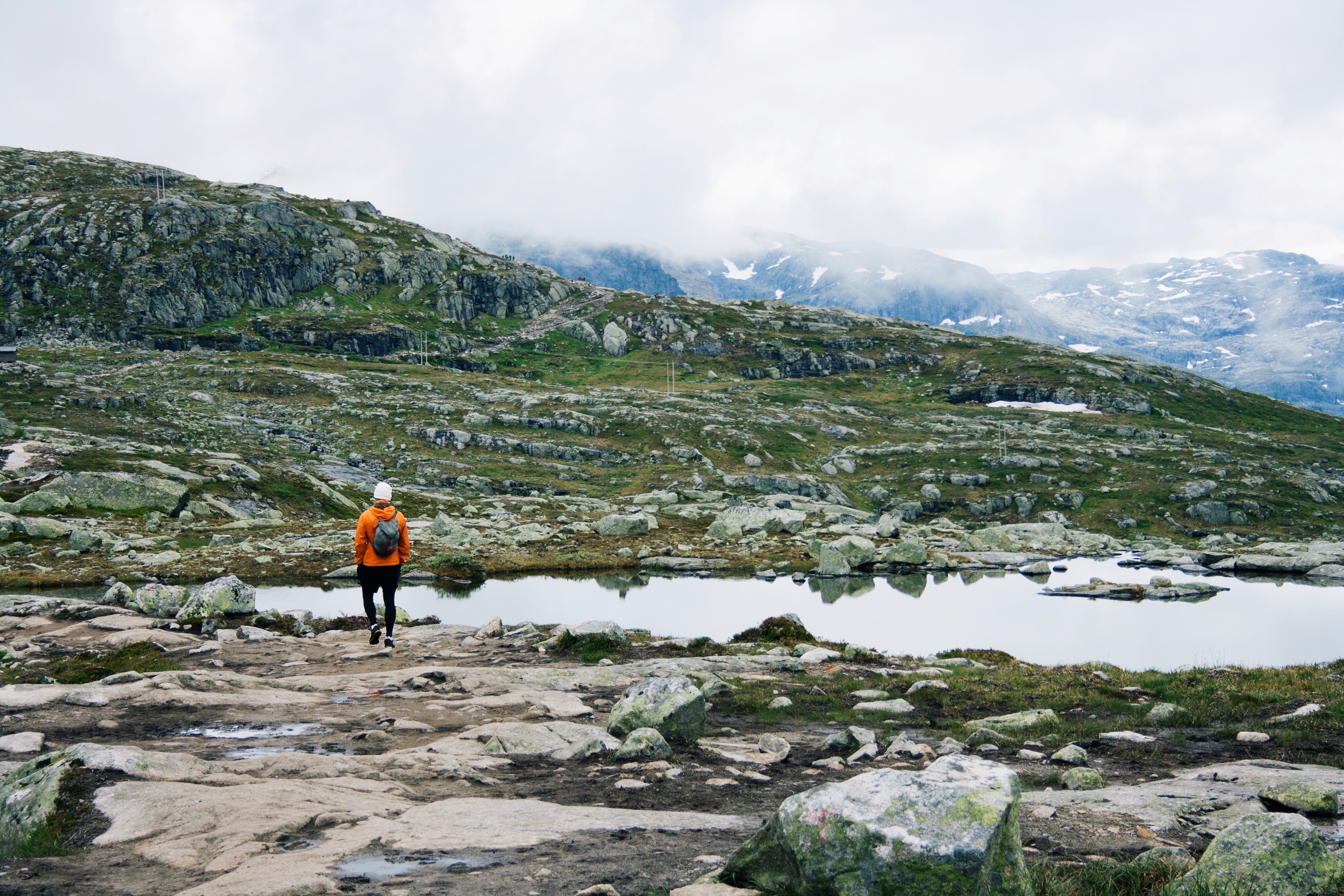 A man in orange jacket hiking in Norway mountains, great outdoors, active lifestyle, hiking trail