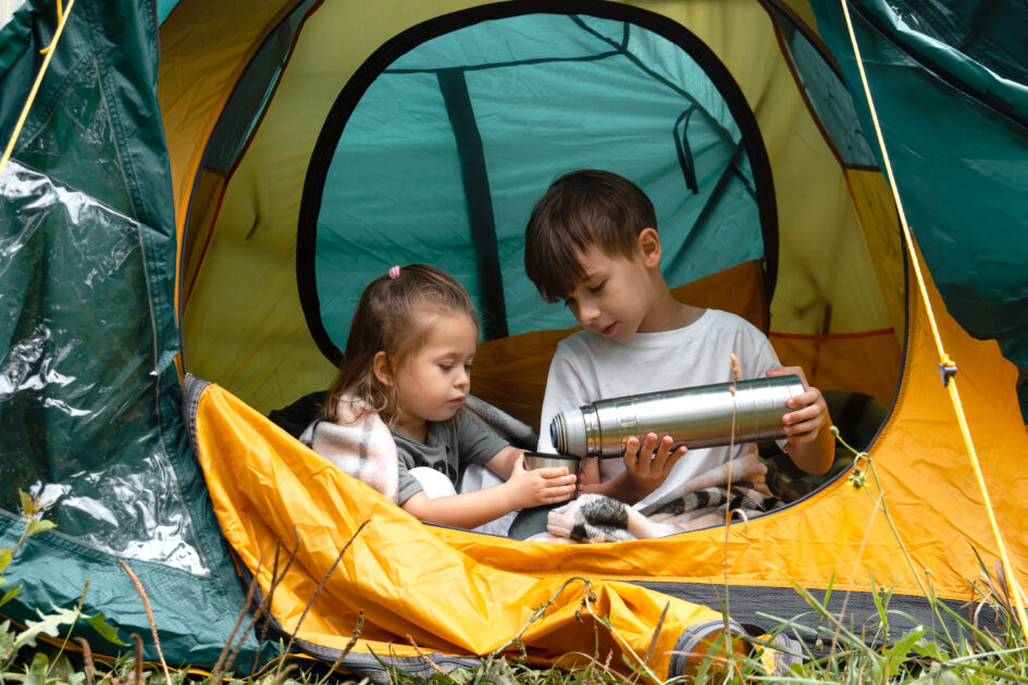 Couple of children sitting in tent. Concept of camping or refugeeism